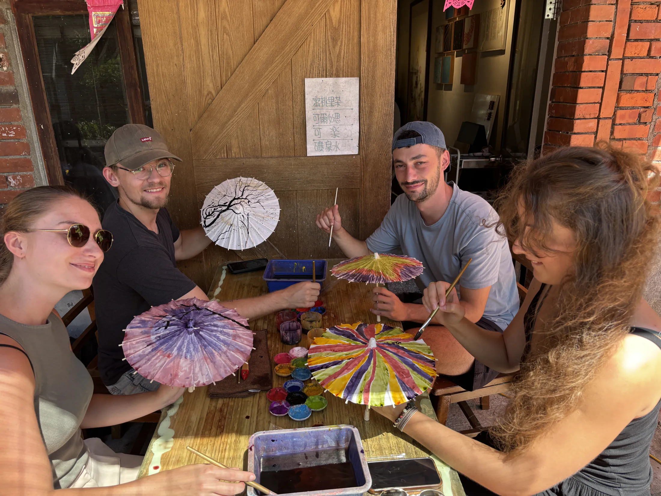 Students painting colorful paper umbrellas together.