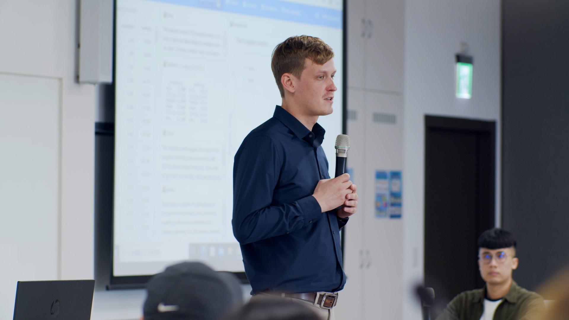 A visiting scholar speaking into a microphone during a presentation at NSYSU.